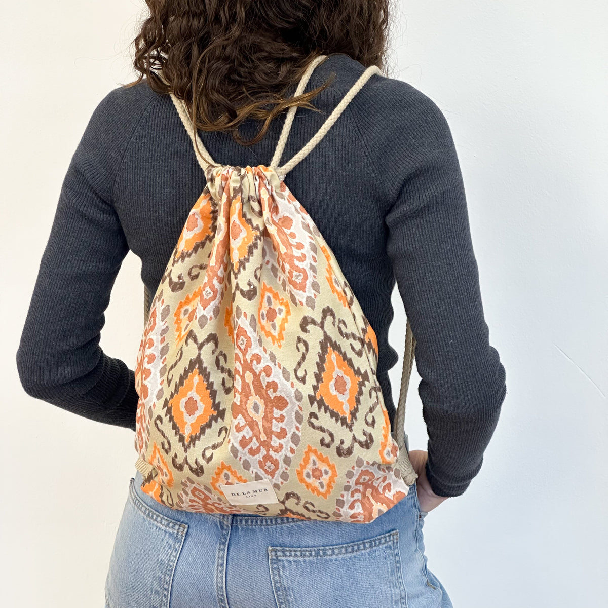 Monedero Ikat, estampado en beige, naranja, terracota, detalle del material y el acabado — De La Mur