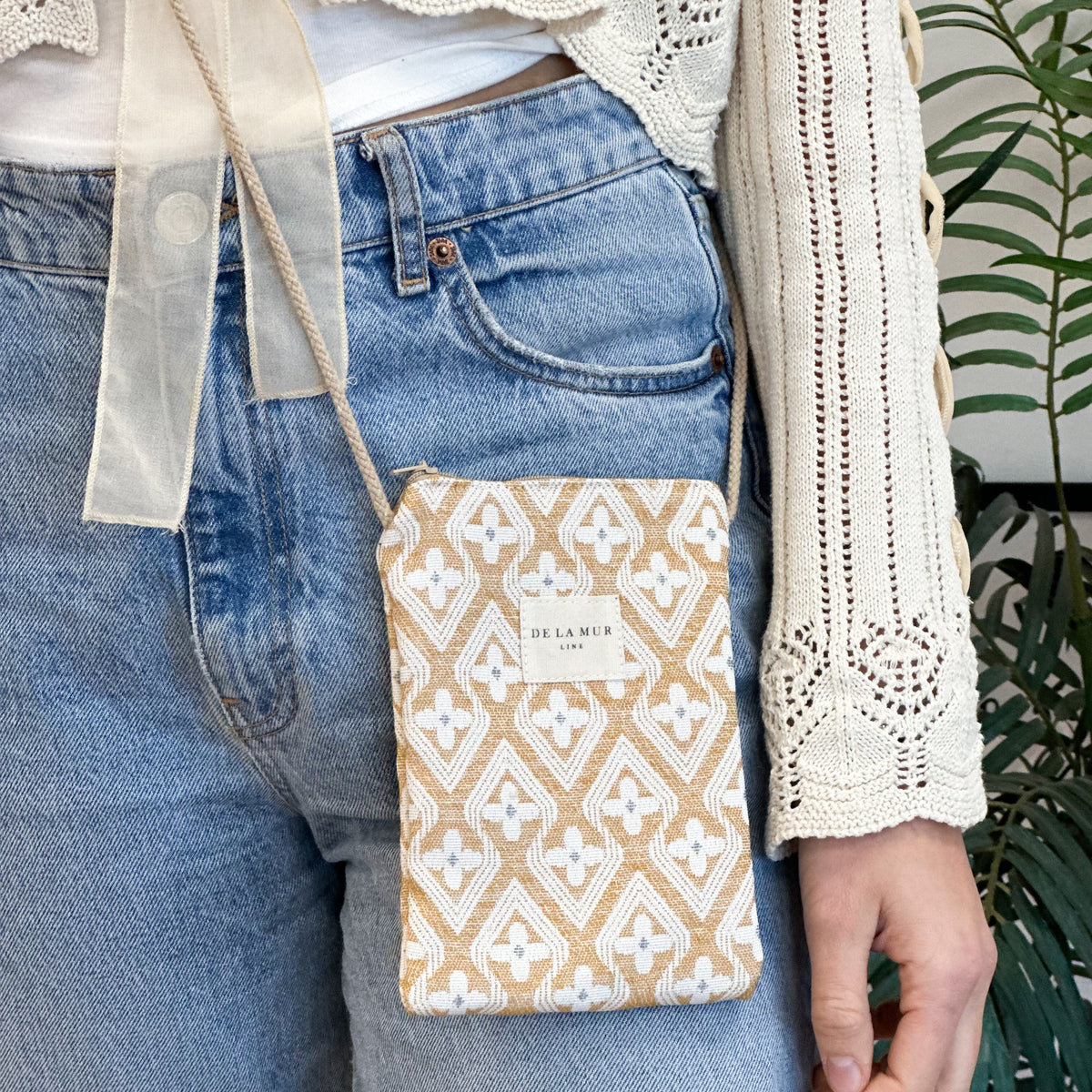 Bolsito porta móvil Raxo, estampado en beige, naranja, negro, detalle del estampado y el material — De La Mur