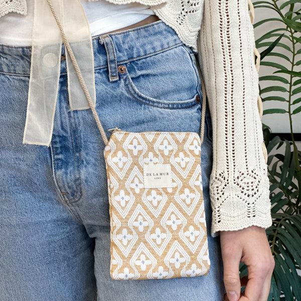 Bolsito porta móvil Raxo, estampado en beige, naranja, negro, detalle del estampado y el material — De La Mur